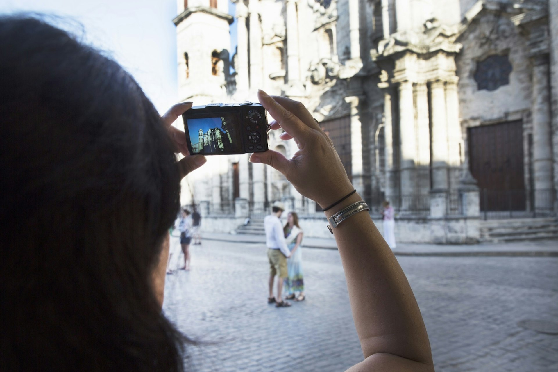 A woman takes a photo of a couple standing in front of The Cathedral of The Virgin Mary of the Immaculate Conception is in Plaza de la Catedral in Cuba. A new Trump administration policy is set to have a major impact on the Cuban economy.
