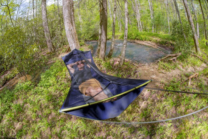 en man lounger i en platt hängmatta täckt med ett insektsnät
