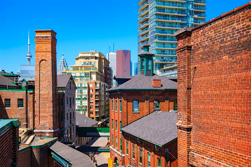 Photo of old brick towers of the chic Distillery District with new condos and downtown skyscrapers in the background 
