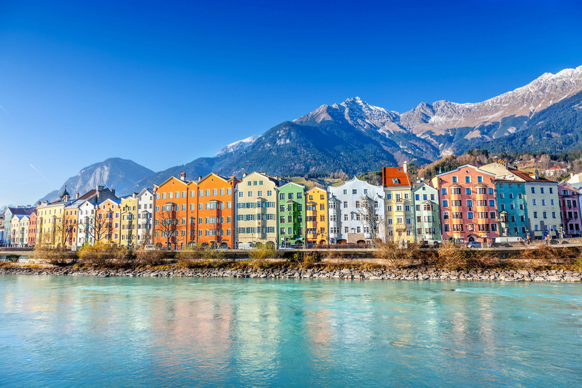 The colourful houses of Innsbruck sit on the river Inn, with the snow-capped Nordkette mountains rising behind