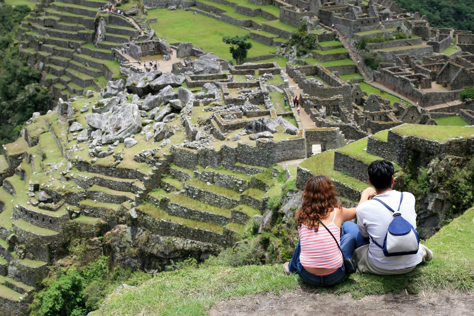 Young couple sitting together on a hill top overlooking Machu Picchu