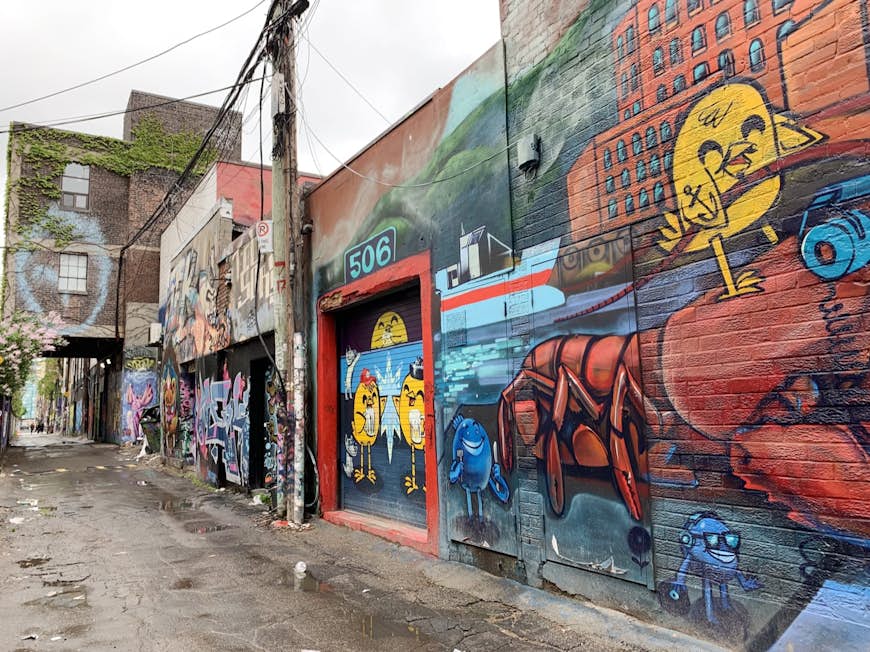 Vibrantly colored street art is seen all over the walls of an alleyway