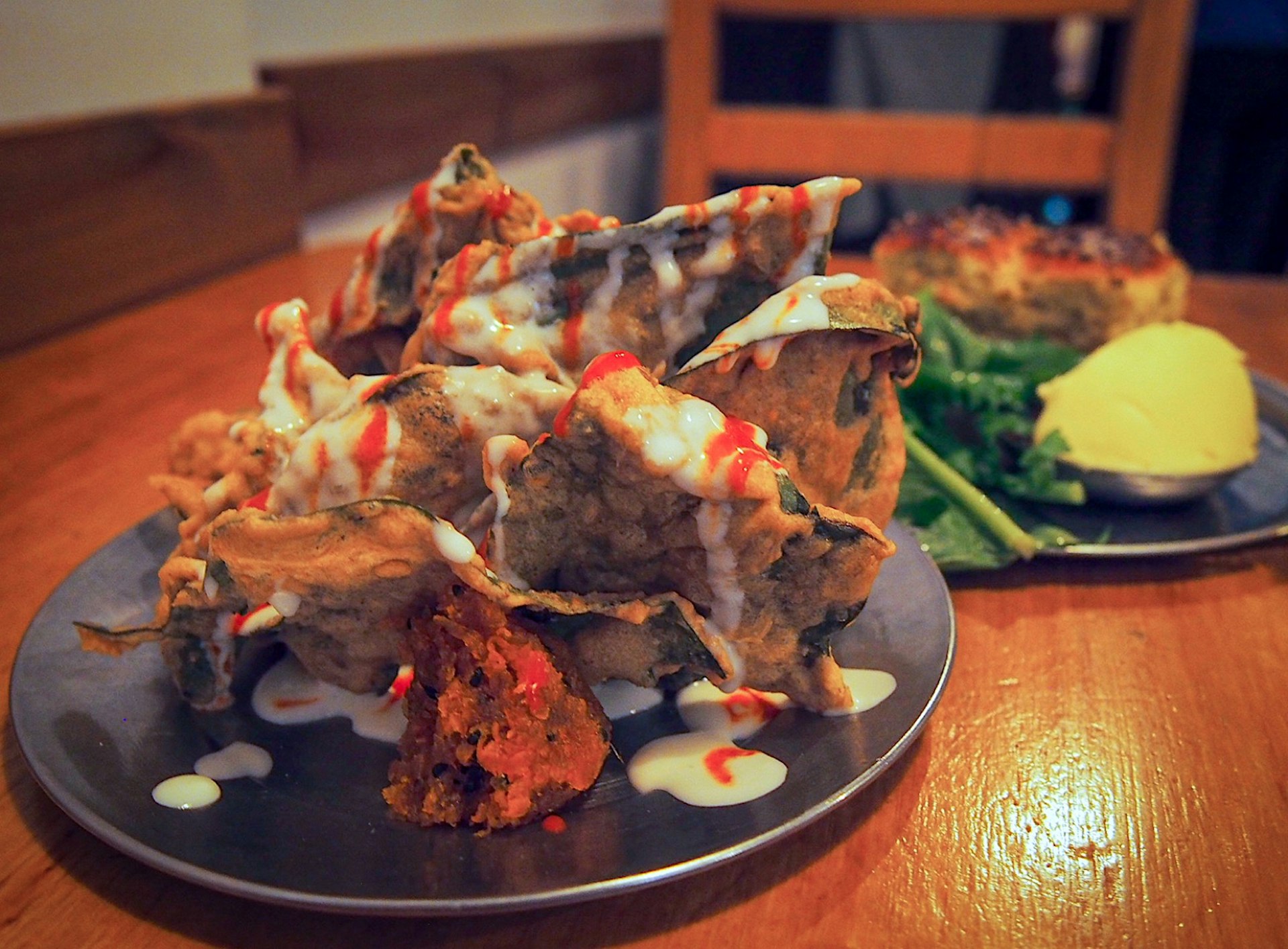 A large dish of food is seen, with several spiky protrusions and lots of dribbling sauces at a Buenos Aires vegetarian restaurant