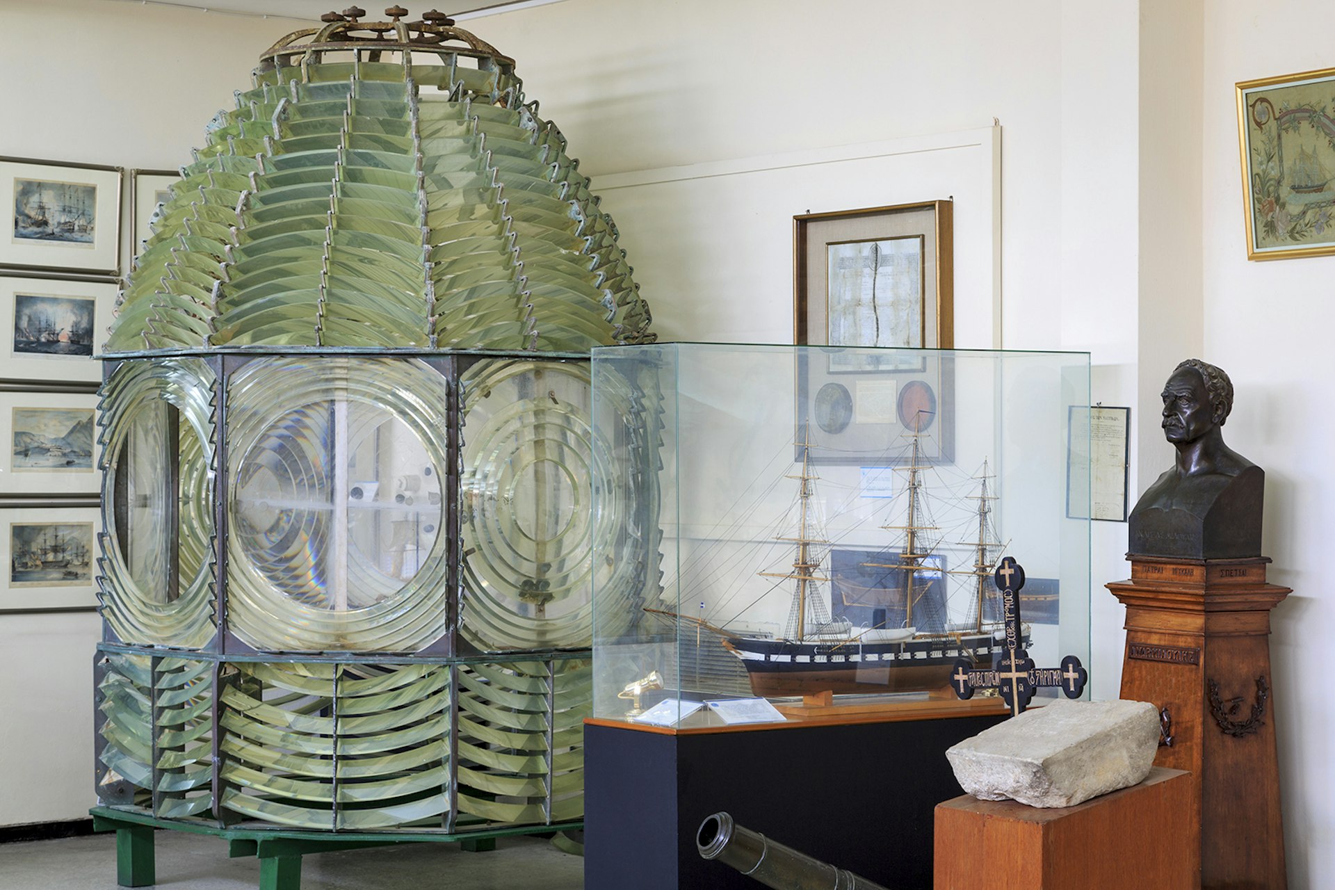 A lighthouse lens sits next to a small model boat at the Hellenic Maritime Museum in Piraeus, Greece.