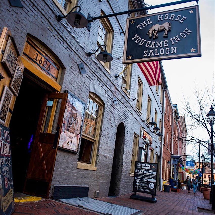 Features - HorseFB-fd2231ec9861 A Georgian brick building is the home of a saloon with a large black sign hanging over the brick street