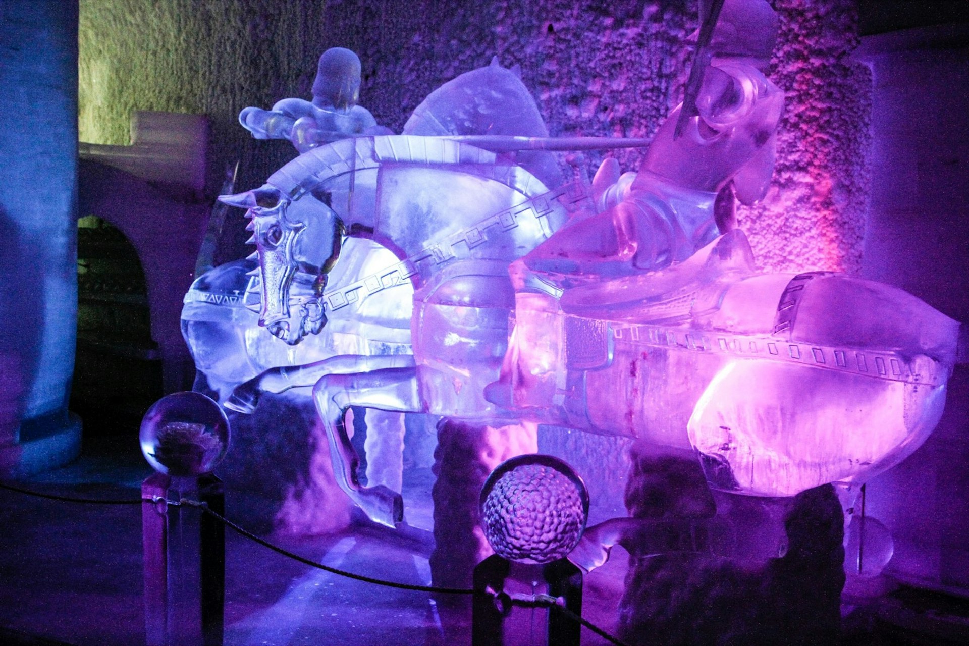 Purple and blue lights illuminate a large ice sculpture of a warrior on a horse in an indoor ice museum at Chena hot springs