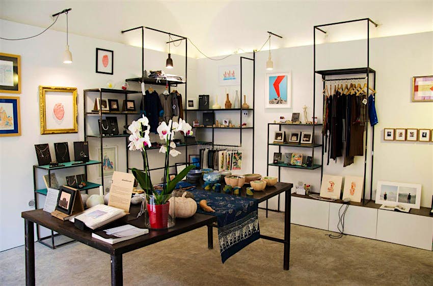 The interior of Materia Mediterranea's shop, with clothing on a rail and art and ceramics on tables and shelves