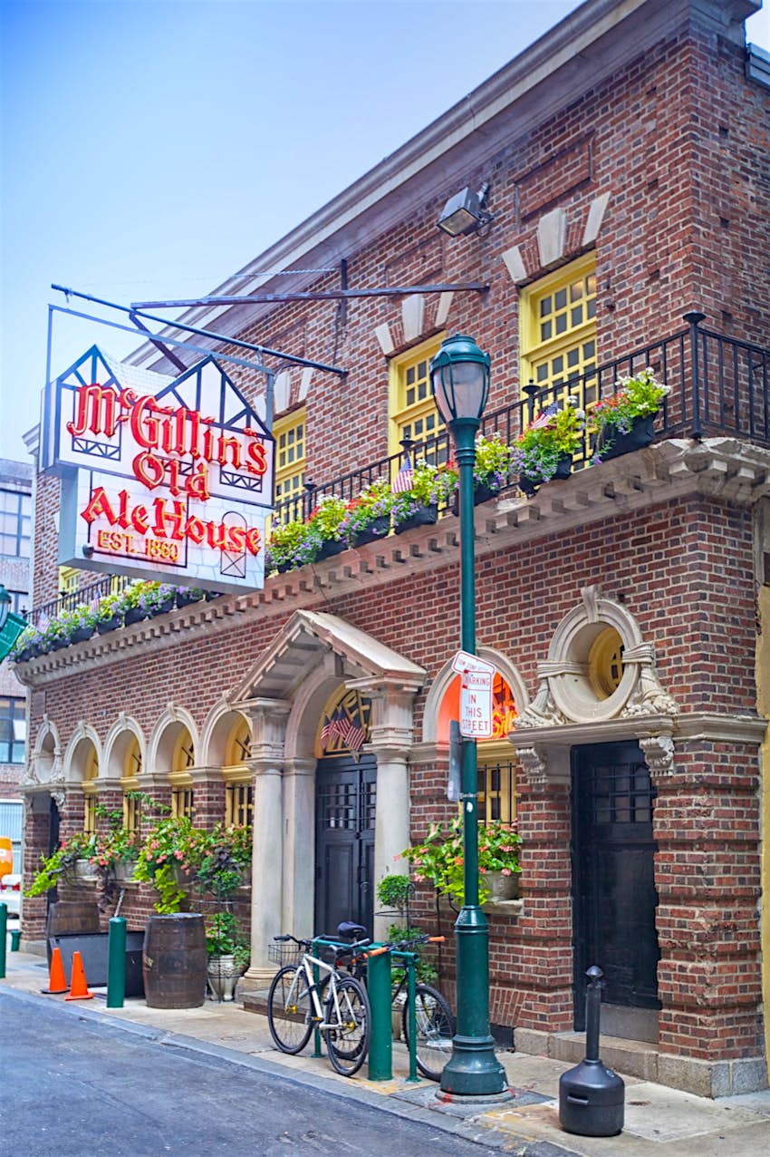 The exterior of McGillin's Olde Ale House features a pretty balcony, gas lamp and a very large neon sign 