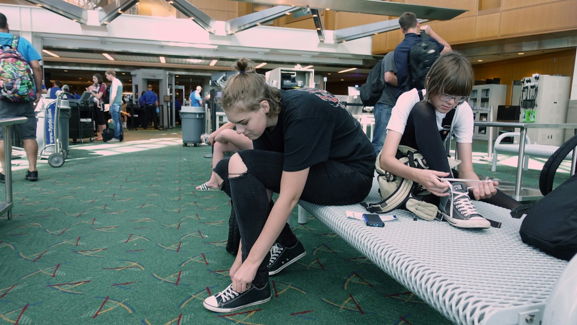 Travelers put their shoes back on after clearing airport security at Portland's PDX
