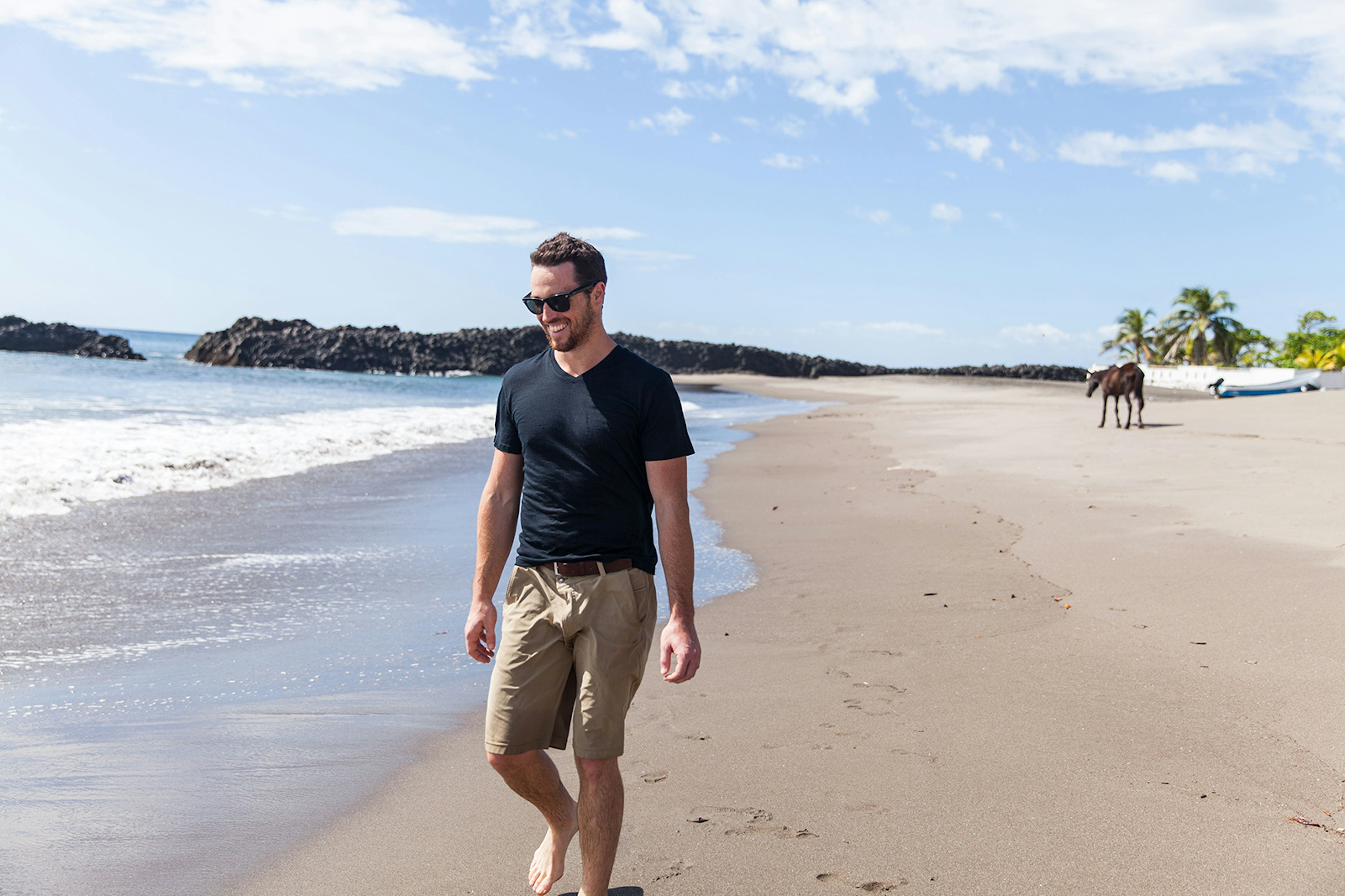 Man walking along a beach while wearing an Unbound Merino shirt; great travel gifts for father's day