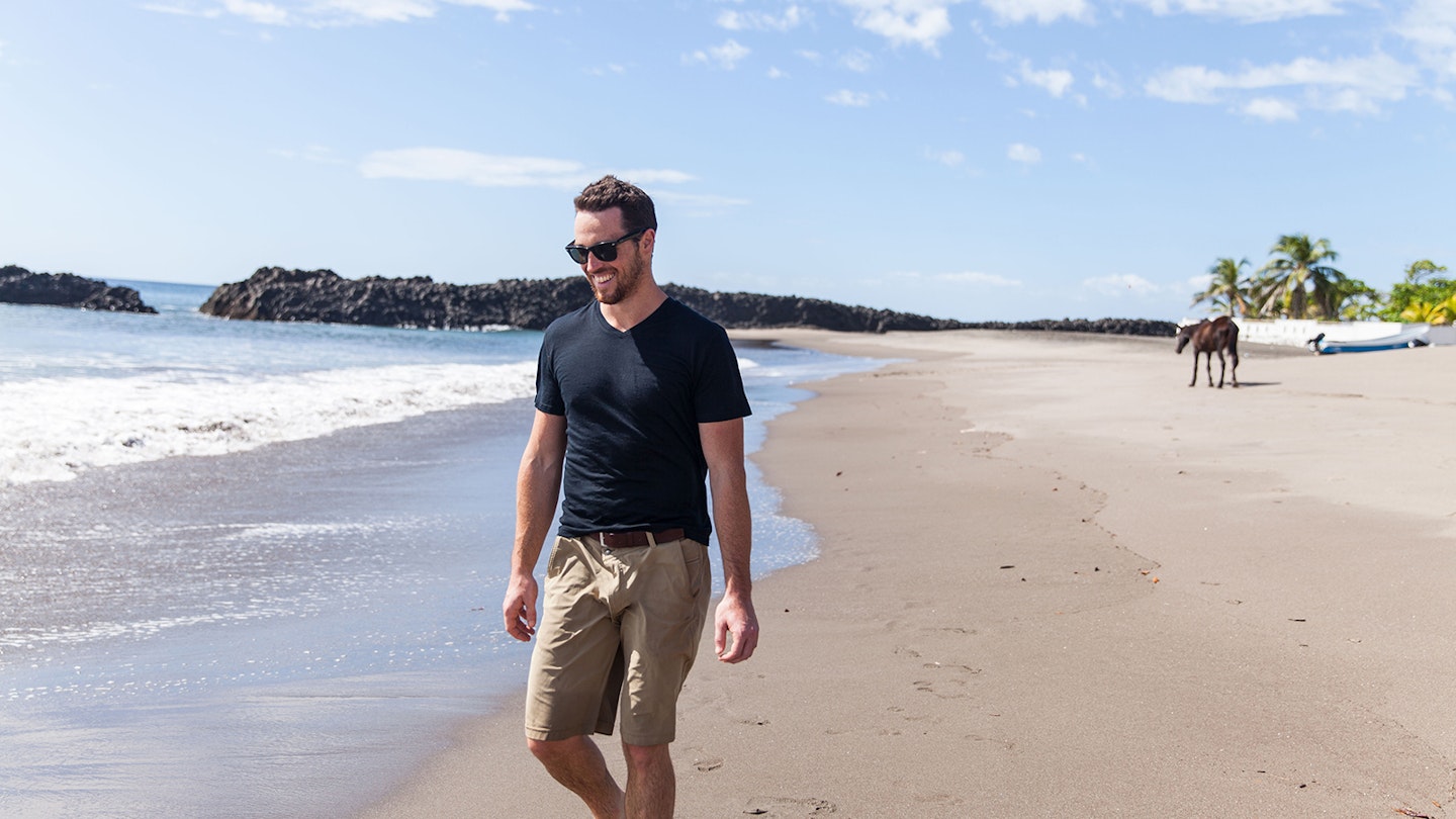 Man walking along a beach while wearing an Unbound Merino shirt; great travel gifts for father's day