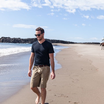 Man walking along a beach while wearing an Unbound Merino shirt; great travel gifts for father's day