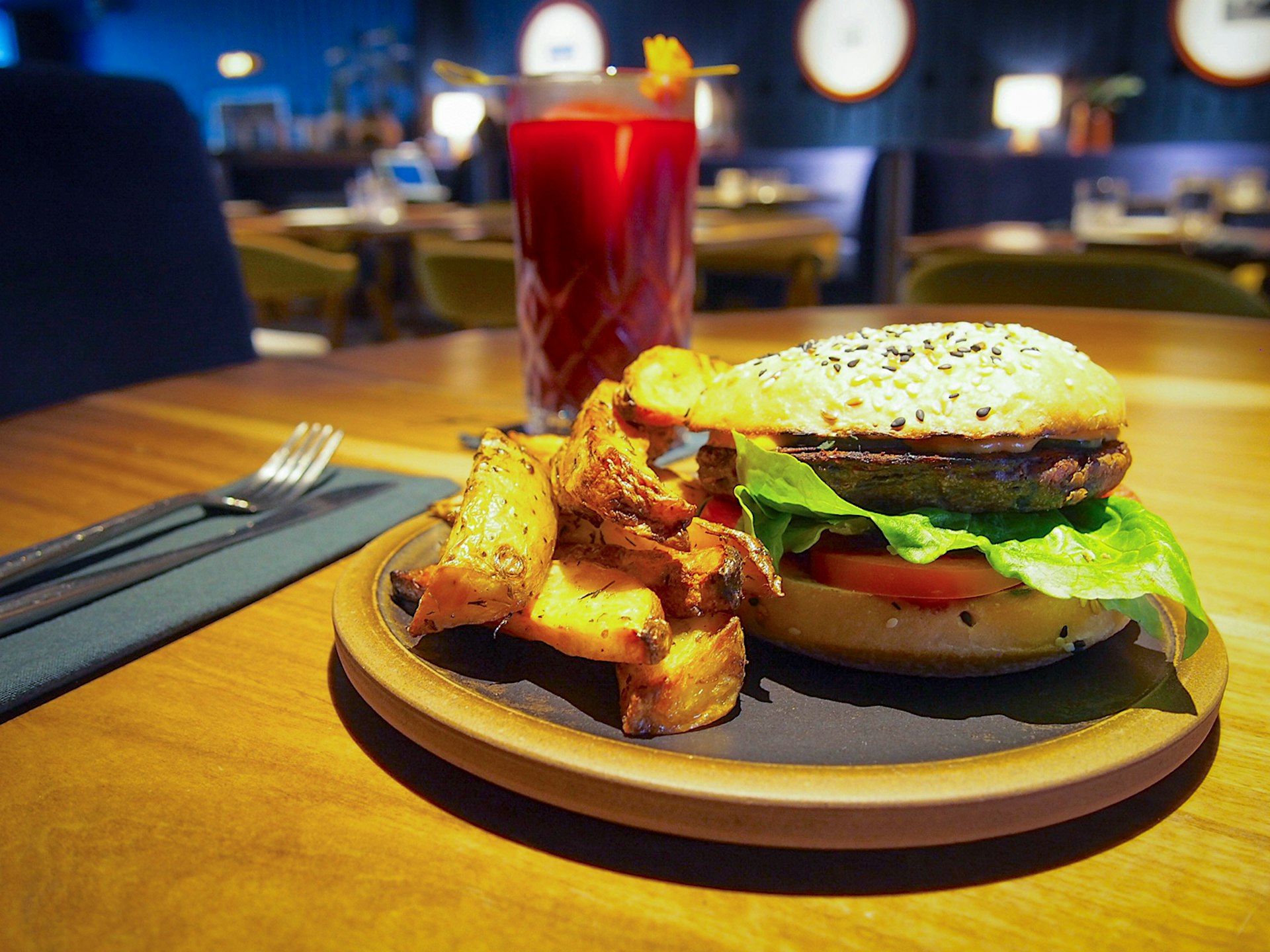 A delicious-looking veggie hamburger is surrounded by thick cut potatoes. The burger has lettuce and tomato on it