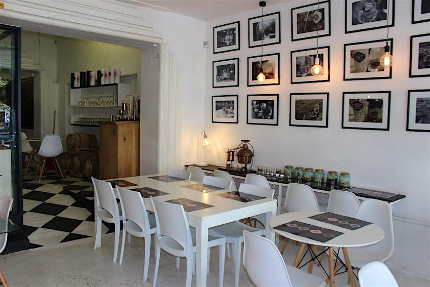 Cape Town gin - A low-key looking room of white walls and black-and-white chequered floor, with simple white tables and chairs for tastings; the wall behind the tale is filled with a series of black and white photos (in black frames with white mounts)