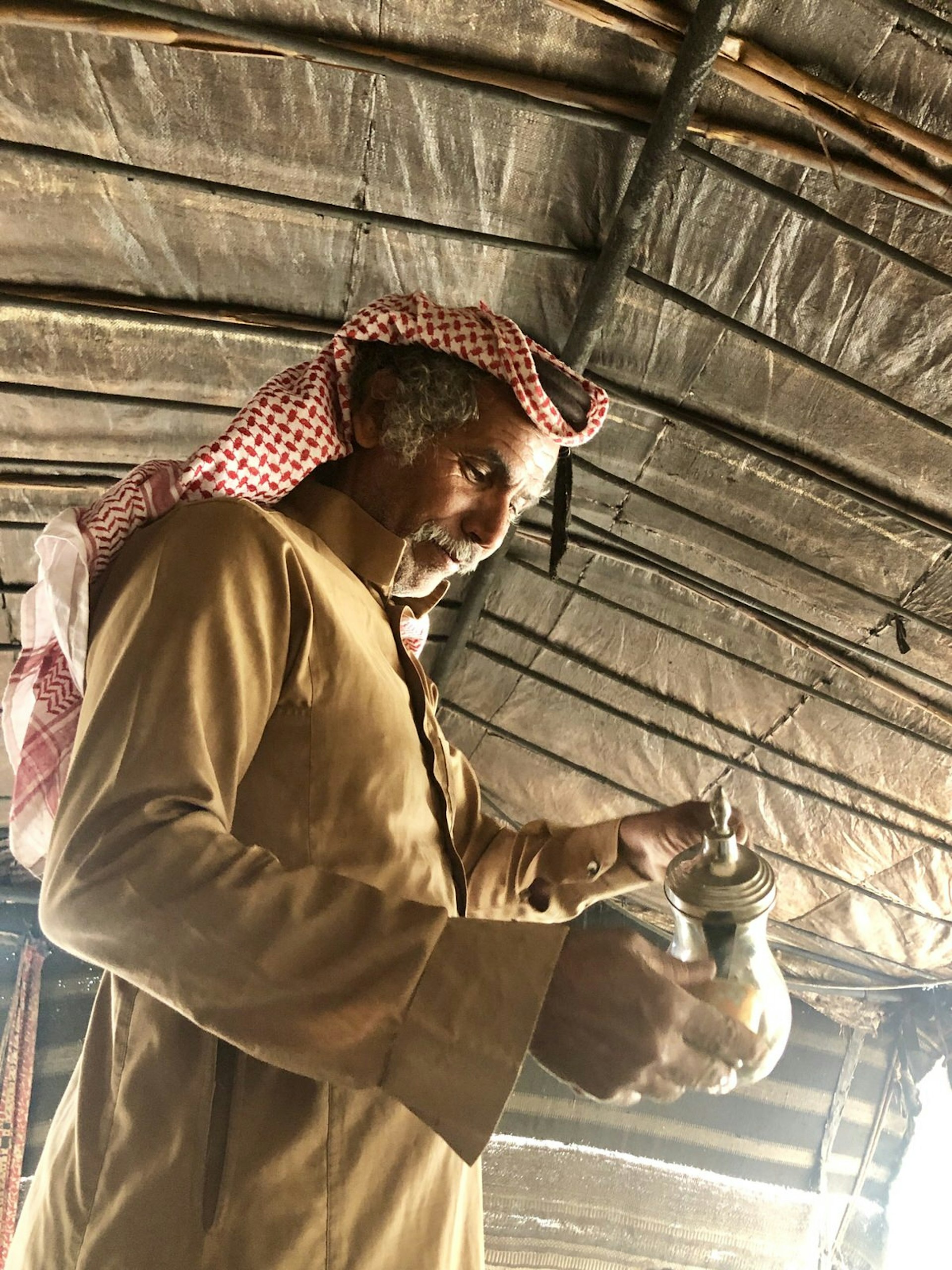 A Bedouin man pours a cup of Arabic coffee, Jordan