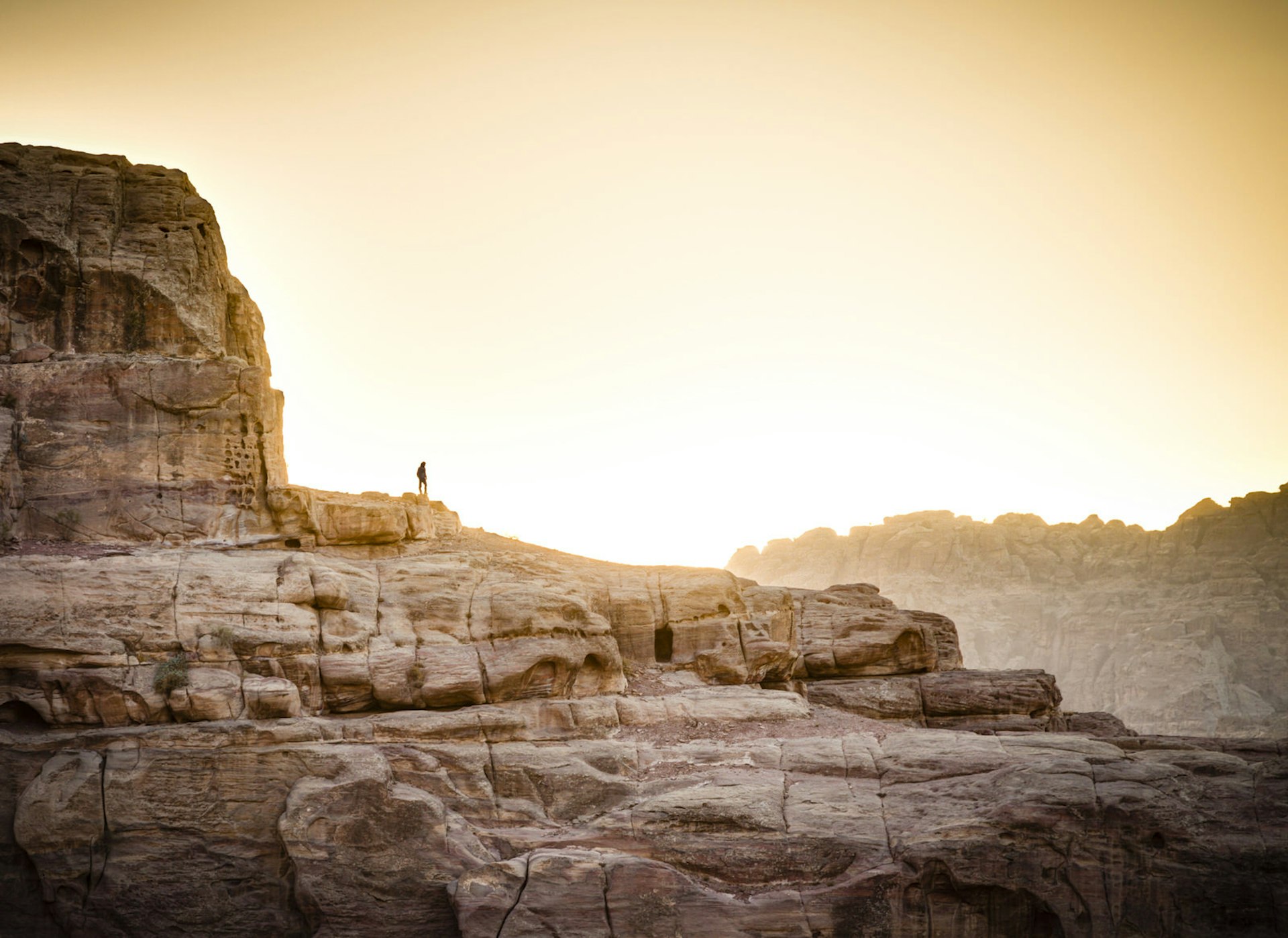 Lone hiker standing on the rock in Petra, Jordan at sunset 