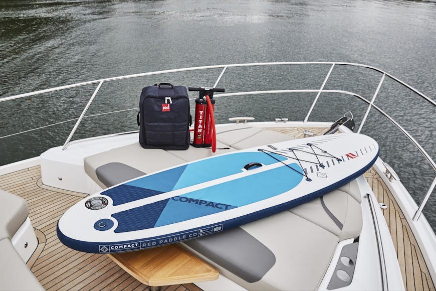 en paddleboard, pack och luftpump vilar på fören på en båt