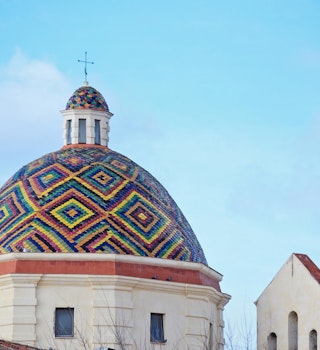 A colorful dome roof under a blue sky; best things to do in Sardinia