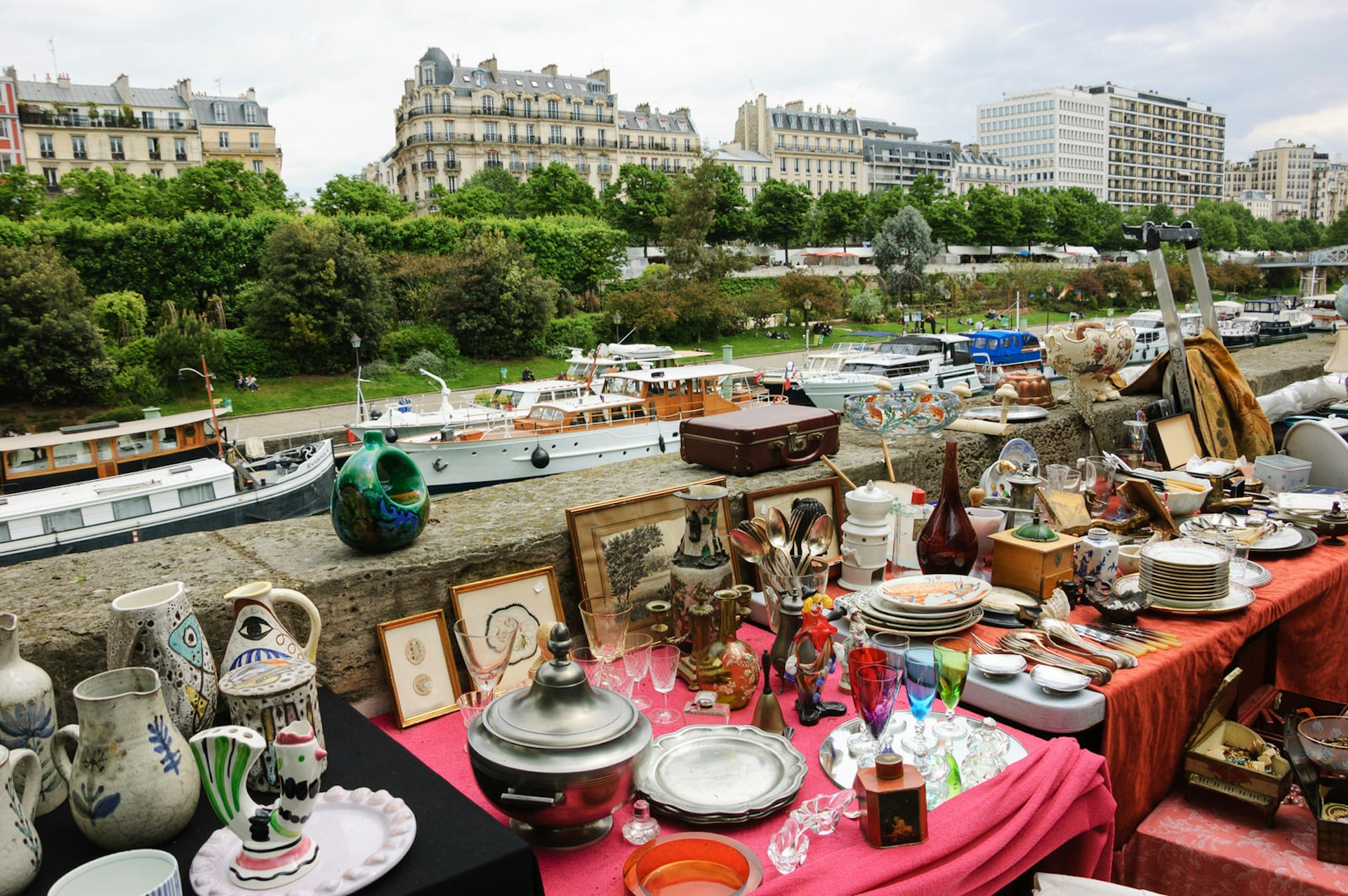 Paris markets - Several tables hold objects such as glasses, picture frames, bowls and dishes alongside the canal