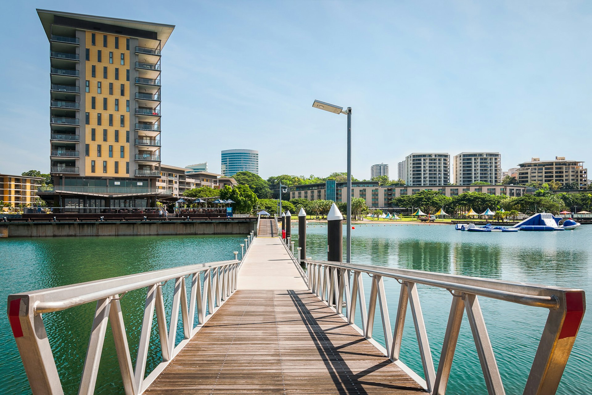 Scenic spot at Darwin Waterfront Wharf with a footbridge over water running from the foreground to the background where it meets a number of modern buildings and skyscrapers