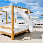 Ibiza spa breaks - white beds and lounges on a white sand beach at Ibiza.