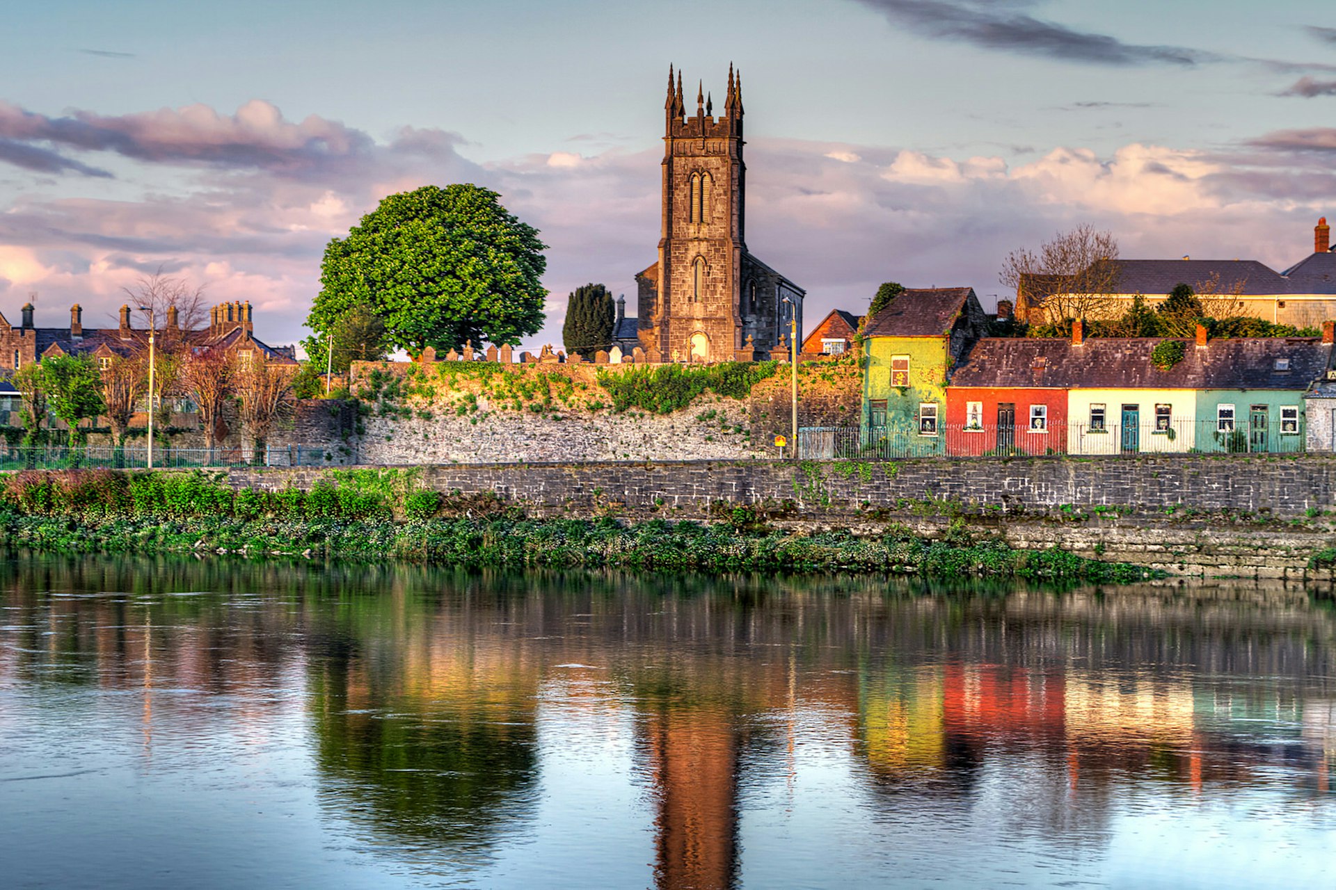 Shannon river scenery in Limerick city, Ireland. A church and colourful houses are viewed from the other side of the river