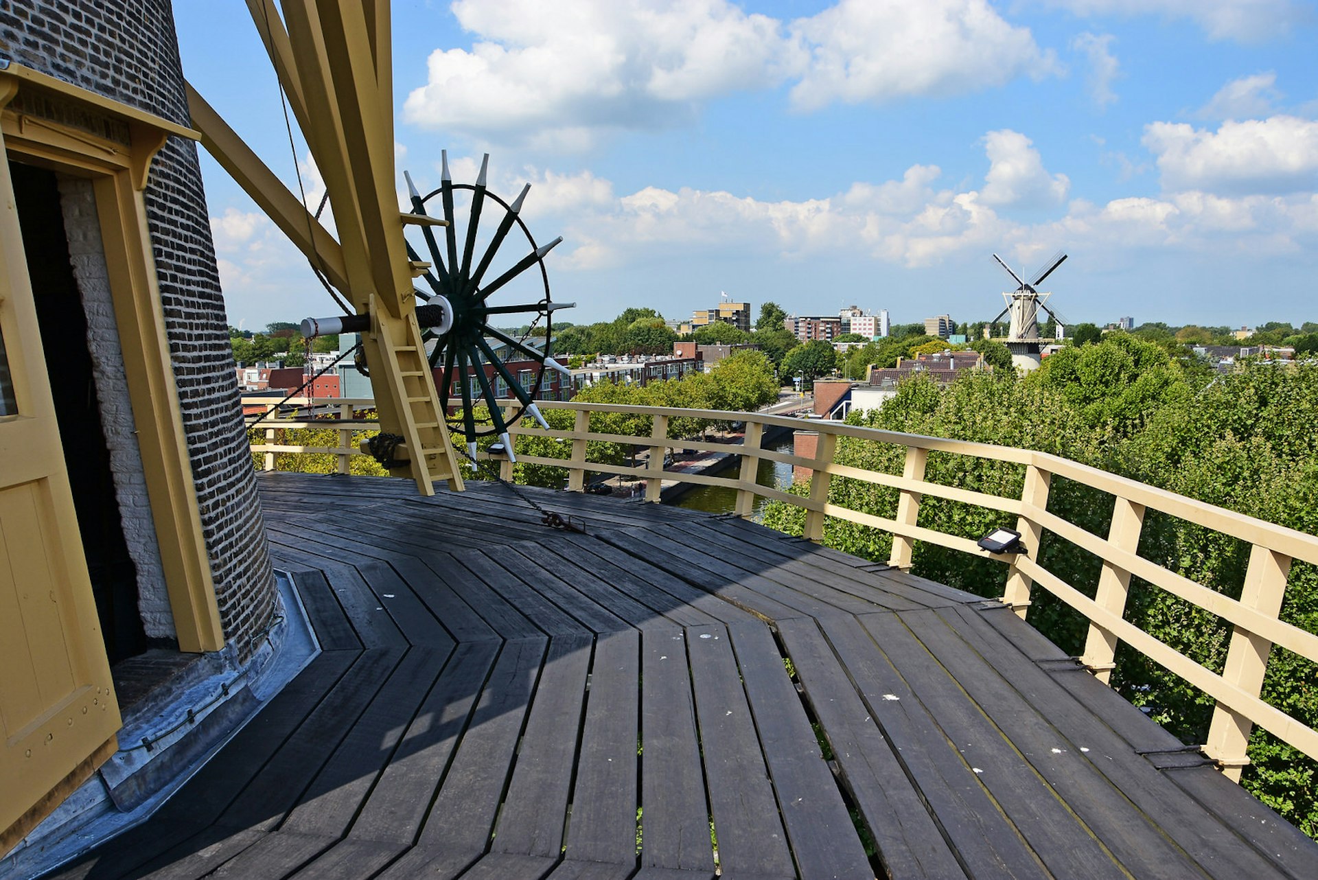 The view from a windmill in Schiedam with trees, houses and a further windmill visible in the distance