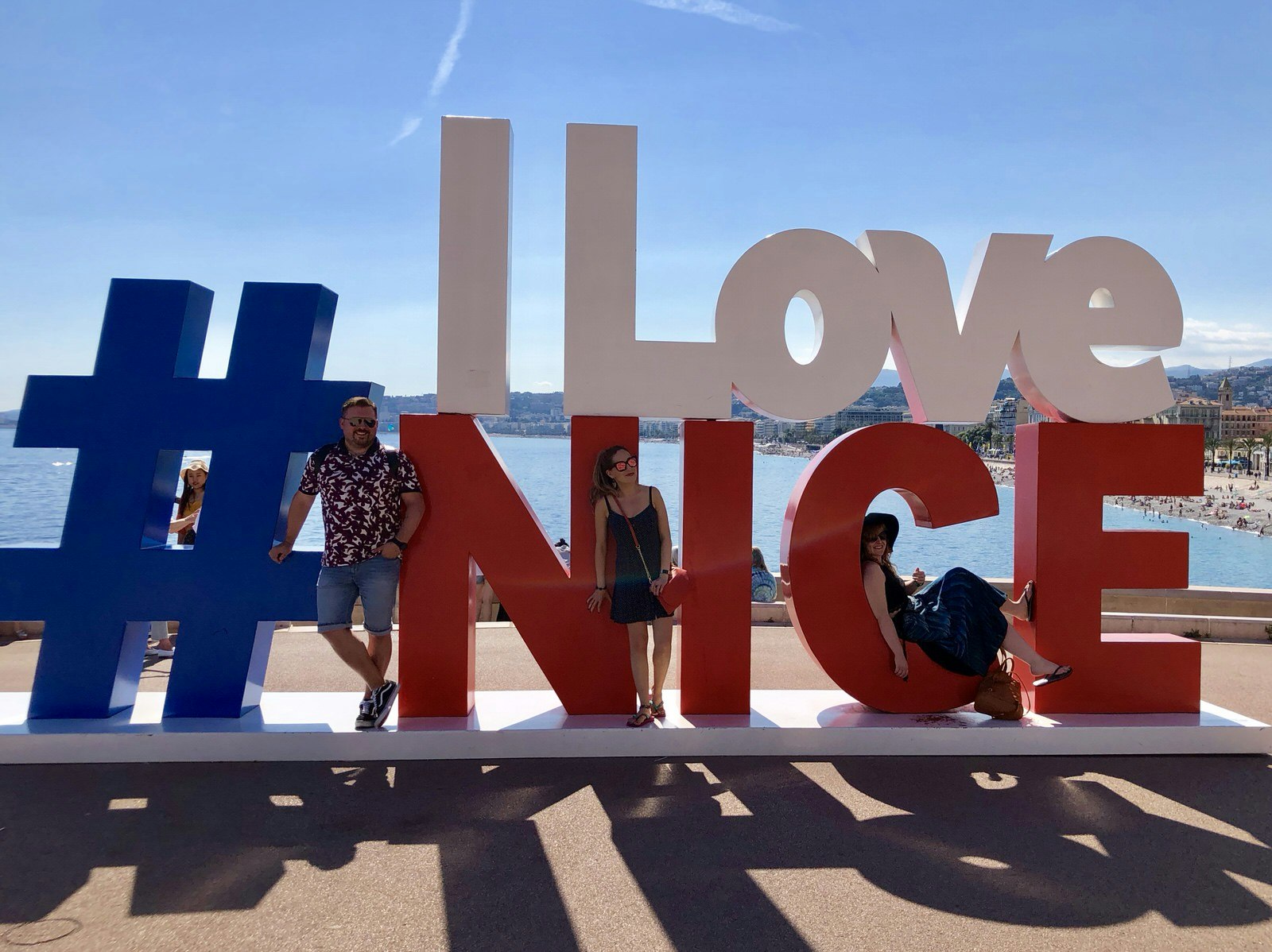 Three people pose at a big sign saying 'I Love Nice'.