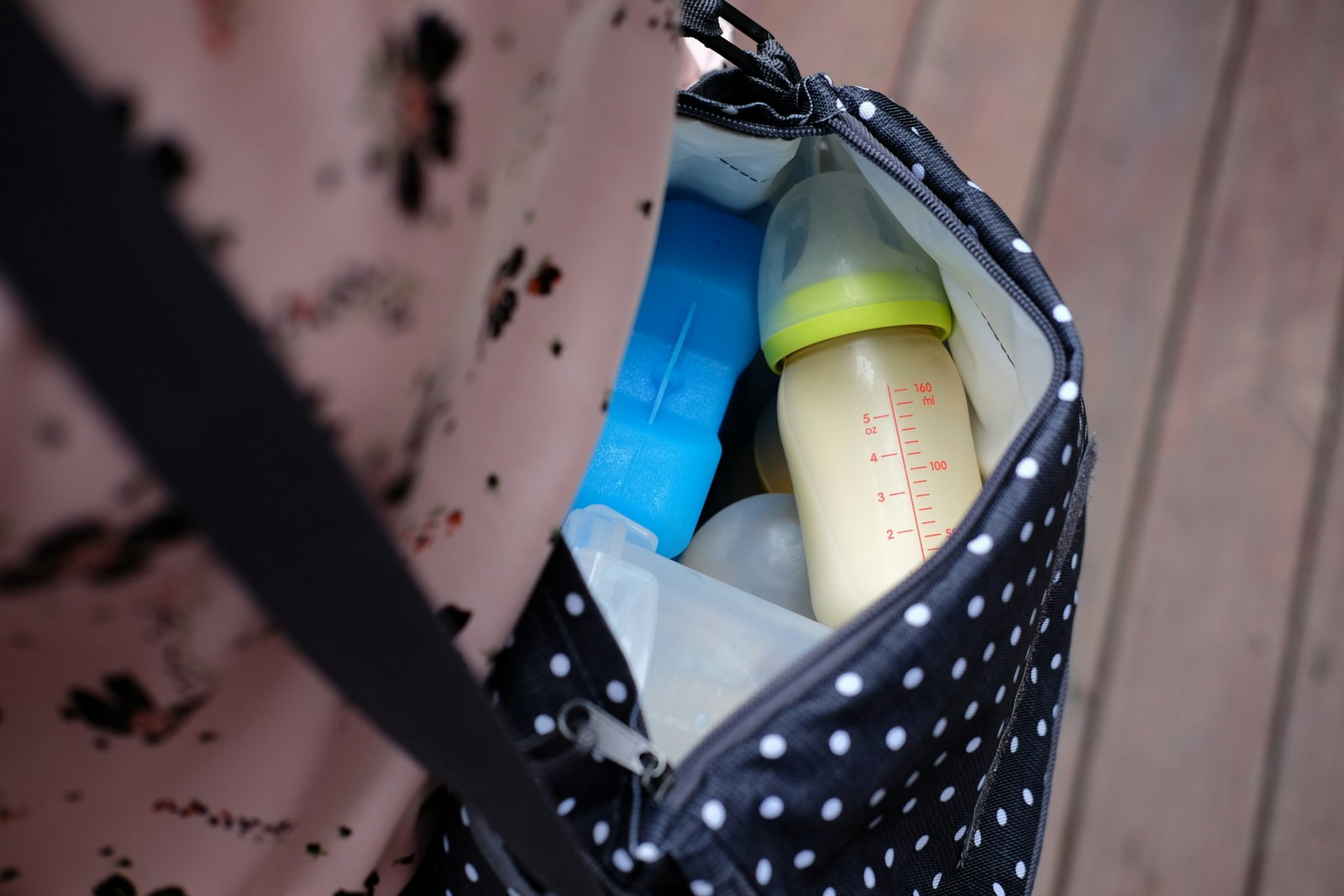 A close up of the interior of a baby bag, with a bottle of breast milk and packet of ice
