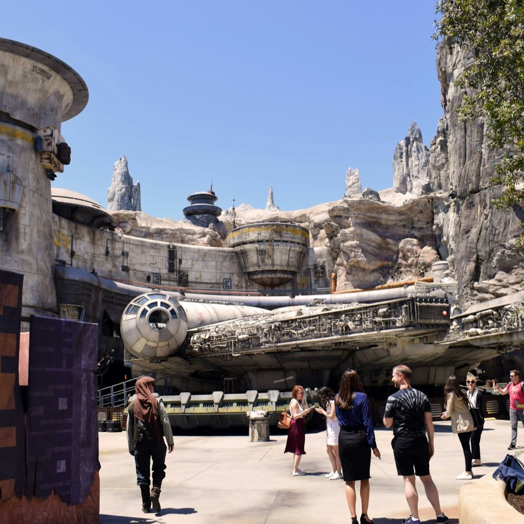 Park visitors walk around a full-size replica of a spaceship; Star Wars theme park