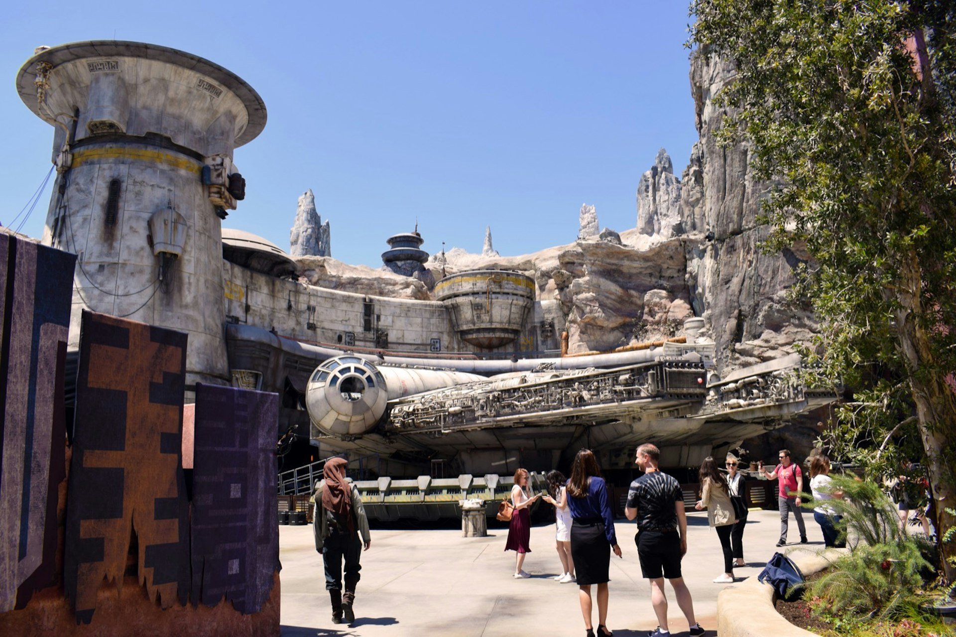 Park visitors walk around a full-size replica of a spaceship; Star Wars theme park