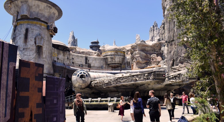 Park visitors walk around a full-size replica of a spaceship; Star Wars theme park