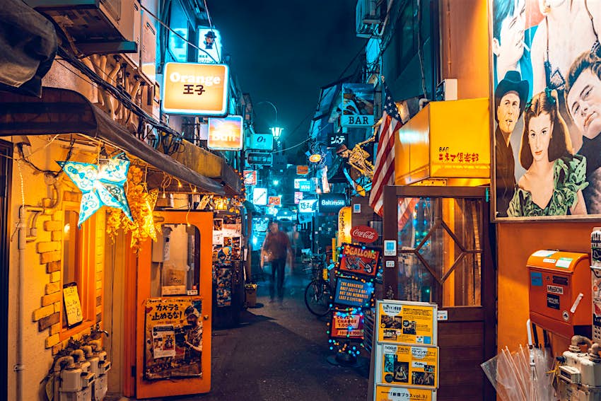 A narrow street in Tokyo's Golden Gai district, with entrances to small, neon-lit bars running along either side
