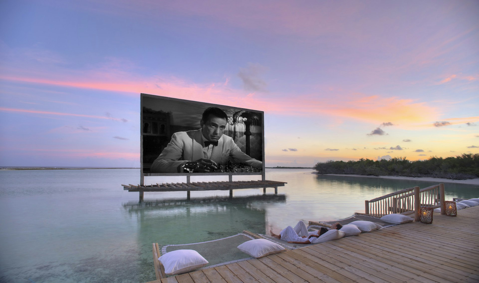 A large screen is set up on a floating terrace showing Casablanca. The sky is lit up by a beautiful sunset in the background.