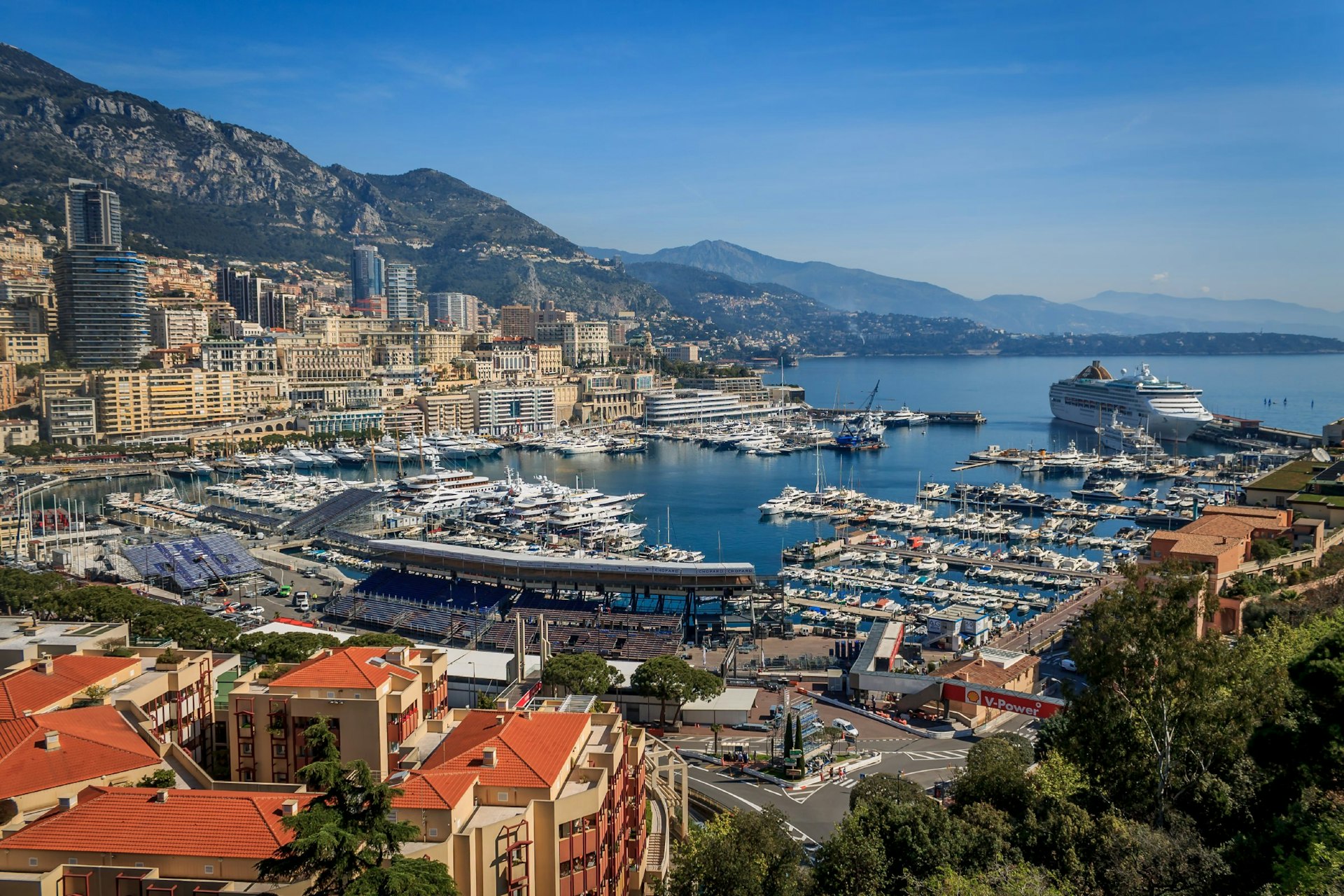 An overhead view of Port Hercule in Monaco as preparations commence for the Grand Prix. Yachts fill the marina and a grandstand overlooks part of the race track.
