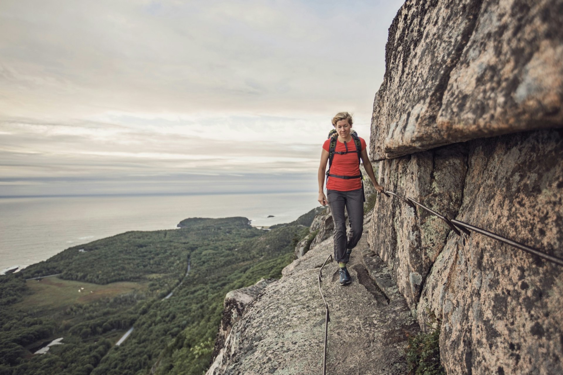 A woman hikes along the cliff edge in Maine's Acadia National Park