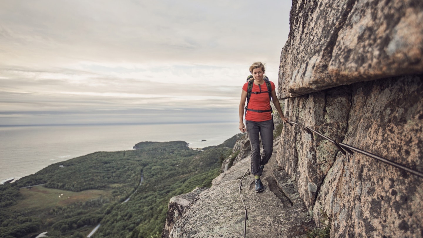 A woman hikes along the cliff edge in Maine's Acadia National Park, Maine