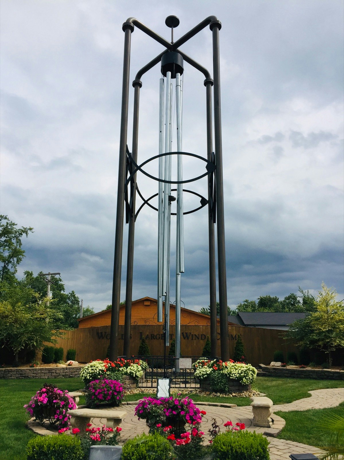 A large windchime stands over pots of flowers, with dark clouds in the sky beyond; midwest travel ideas
