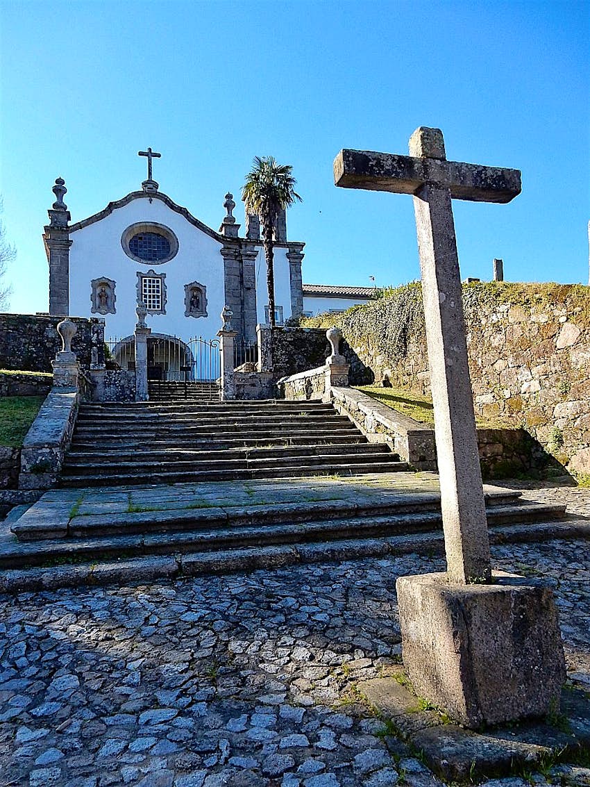 A view up steps to a hotel housed in a former convent; there is a stone cross in the foreground.
