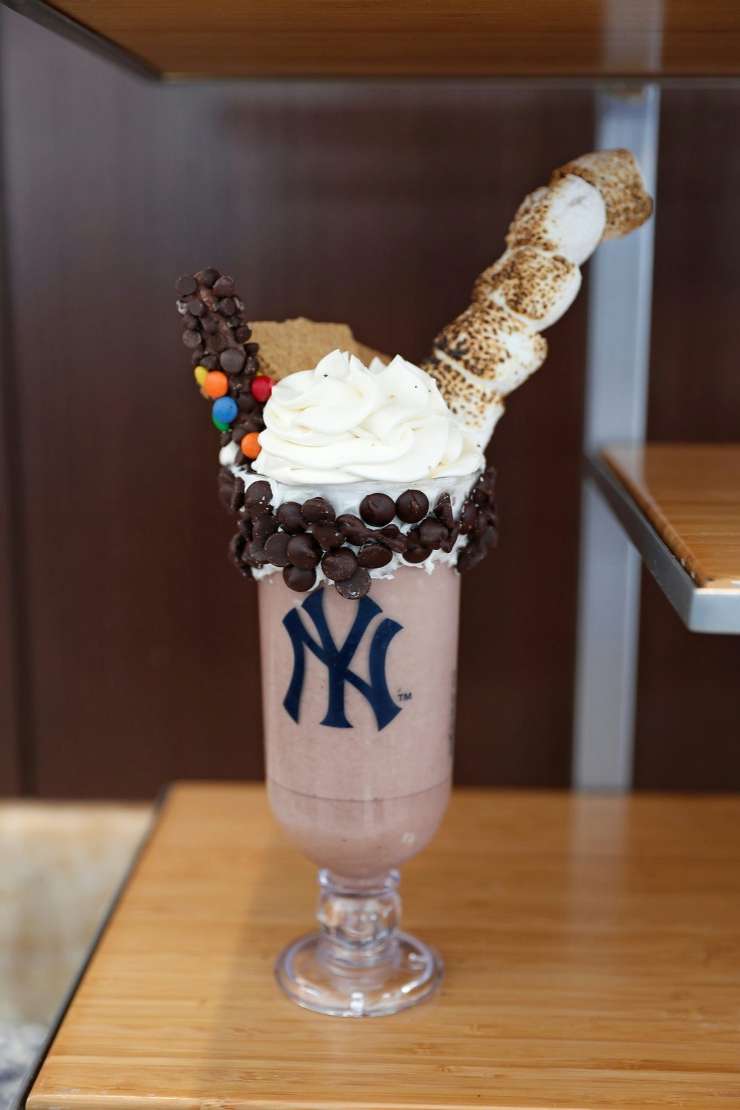 A chocolate shake rimmed with chocolate chips, topped with whipped cream and toasted marshmallows; ballpark food