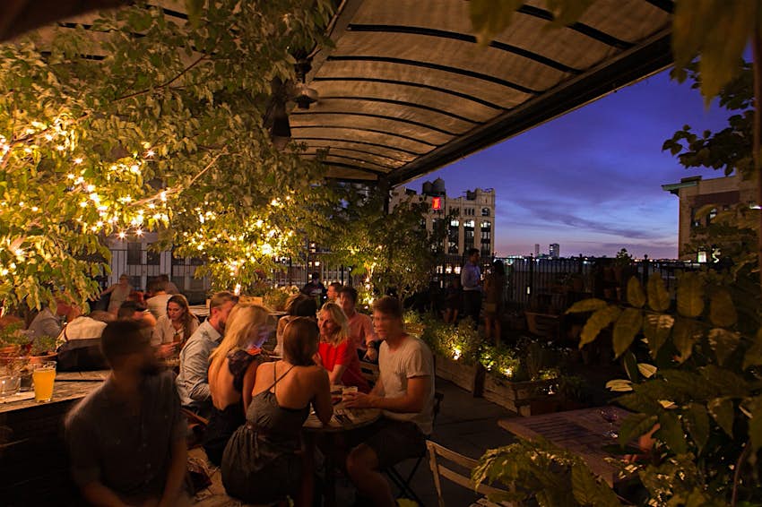 People under an awning on a rooftop bar; best rooftop bars in New York City