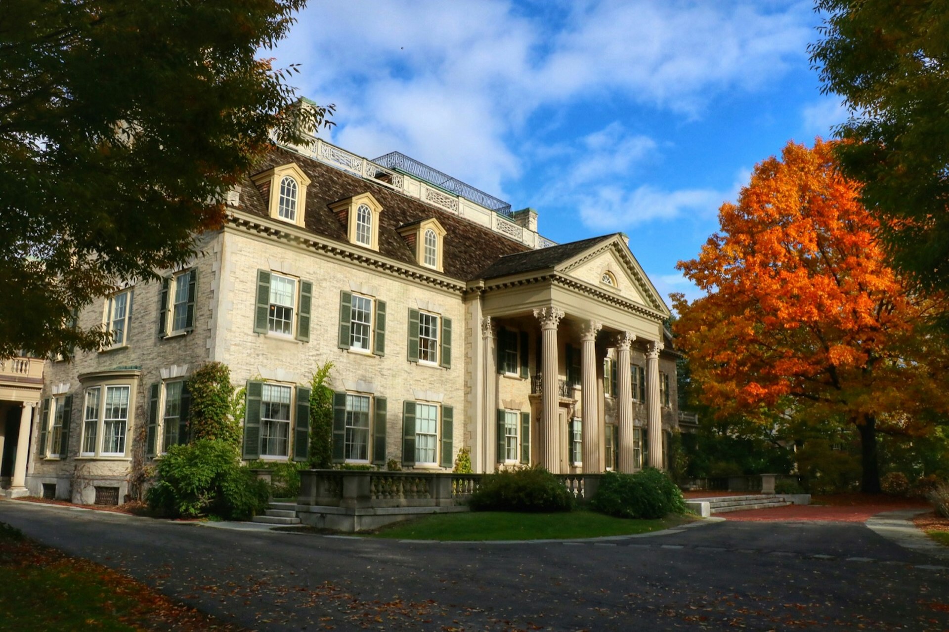 An exterior of the George Eastman Museum, with orange leaves surrounding