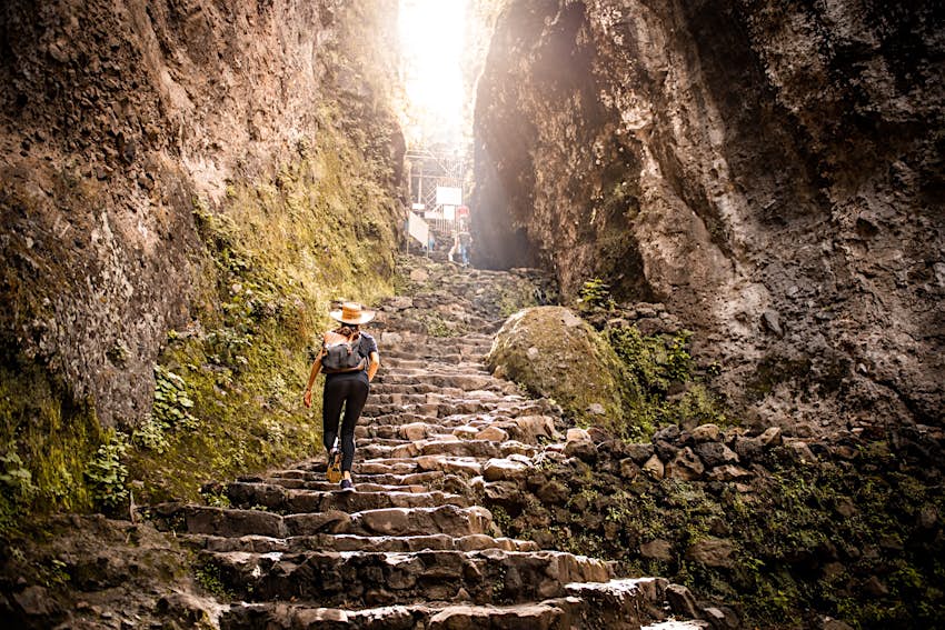 A female traveller climbs crumbling steep steps in El Tezpoteco, Mexico.
