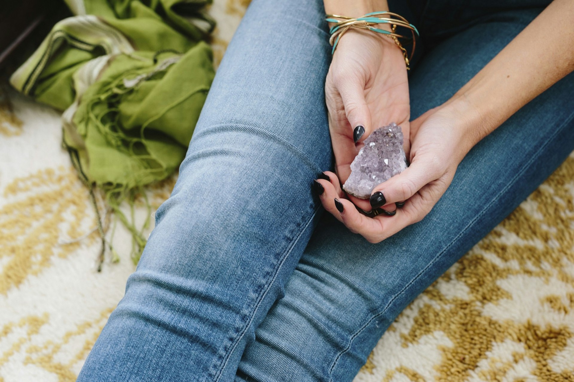 A woman with her legs crossed holds an amethyst crystal on her lap; sacred spaces