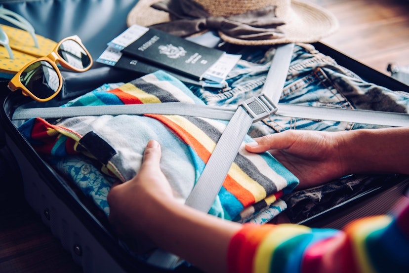 A woman packs a striped, colorful shirt into a suitcase, with sunglasses and a passport nearby; tips for a long-haul flight