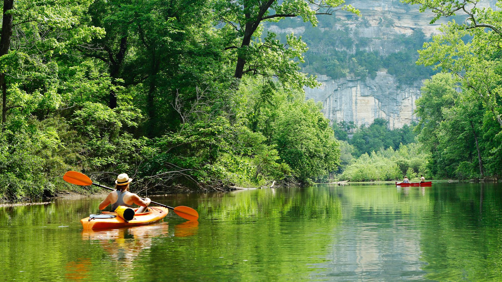 Kayakers on a river surrounded by green trees; summer escapes in the Southern US