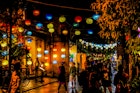 Colourful paper lanterns are strung across the street creating a warm atmosphere in the darkness