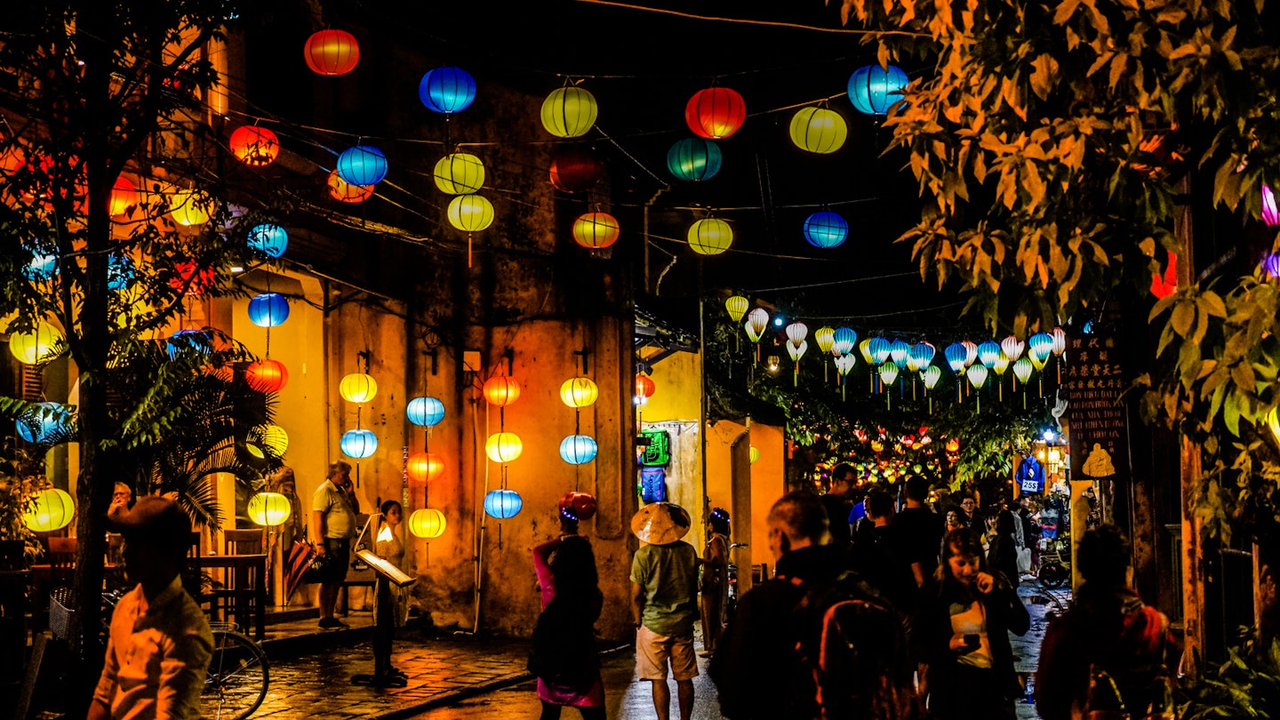 Colourful paper lanterns are strung across the street creating a warm atmosphere in the darkness