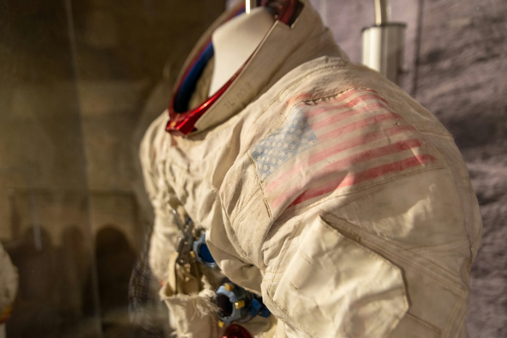A closeup of an Apollo-era spacesuit, there's a faded American flag emblem on the left shoulder