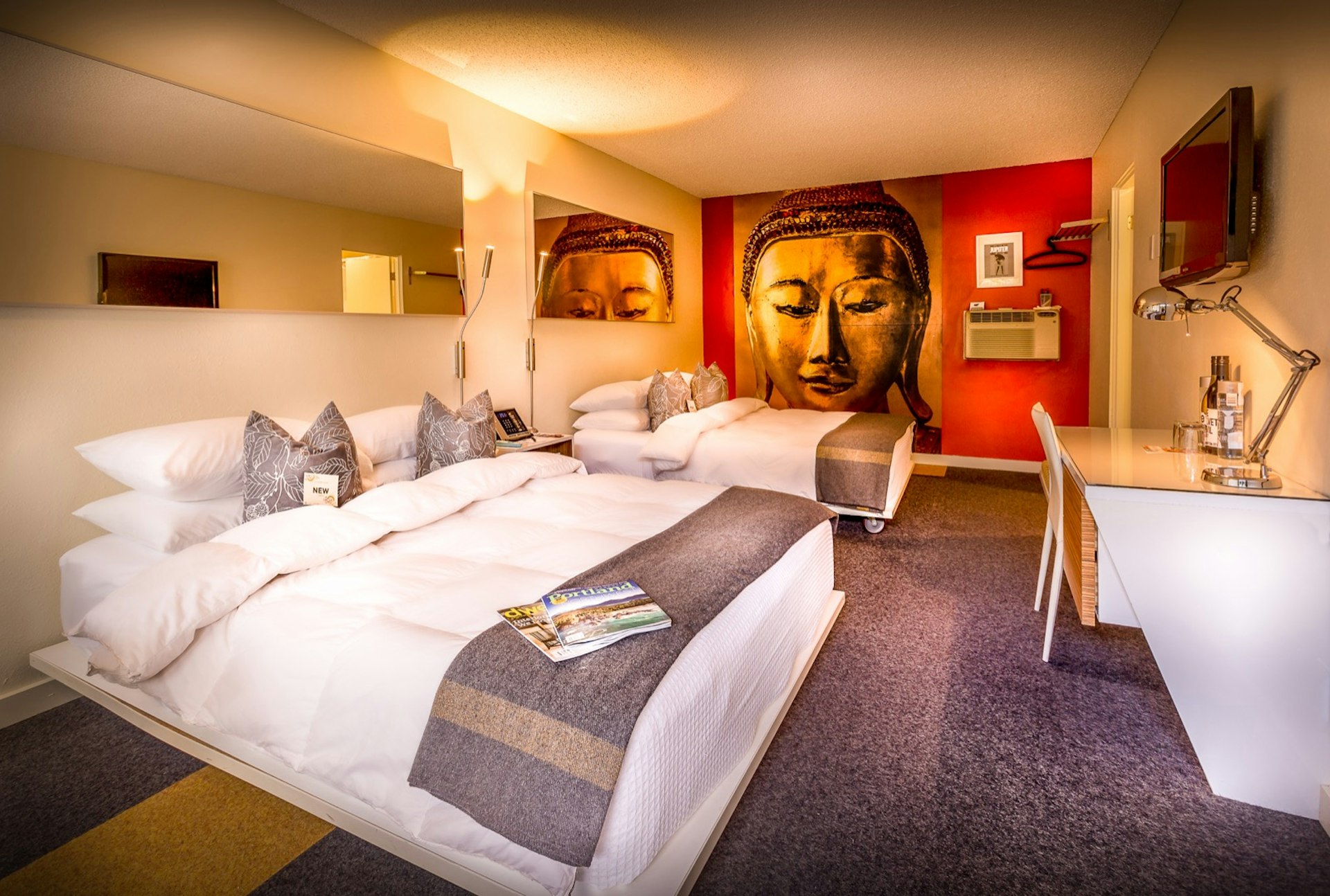 Inside a room at The Jupiter, with a red accent wall painted with the face of Buddha